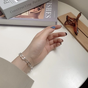 Close-up of a minimalist S925 sterling silver flat link chain bracelet worn on a wrist