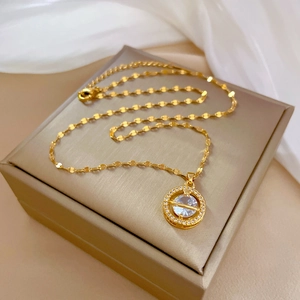 Close-up of a gold planet necklace with micro-pave crystals on a beige jewelry box