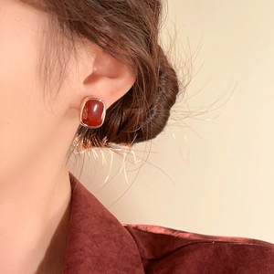 Close-up of trapezoidal reddish-brown resin earring with gold-plated metal inlay on ear