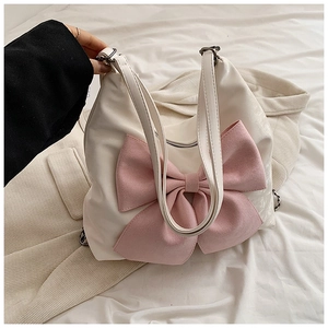 Close-up of white PU leather shoulder bag featuring a large pink decorative bow detail