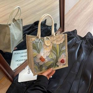 Detail of linen tote bag featuring 3D floral embroidery and wooden button closure