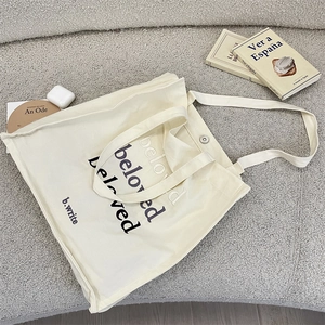 Detail of beloved letter embroidery on cream canvas tote bag with magnetic closure