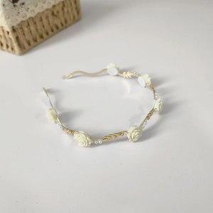 Detail of golden wavy headband with beige roses and small pearl beads decoration