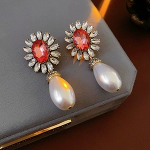 Détail de boucles d'oreilles vintage avec strass rouges et perles dans une boîte à bijoux