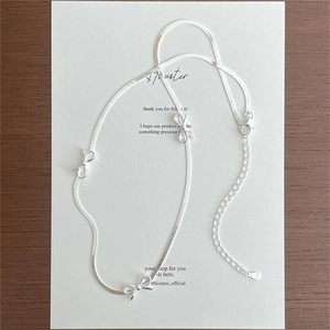 Detail of silver S925 sterling silver snake chain necklace featuring bow-knot pendants