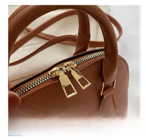 Close-up of caramel brown crocodile embossed shell bag with golden metal double zippers