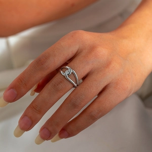 Detail of silver geometric leaf knot ring with rope texture on a model's hand