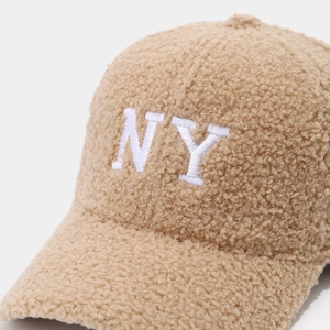 Gros plan sur la texture sherpa épaisse et la broderie NY blanche sur une casquette kaki