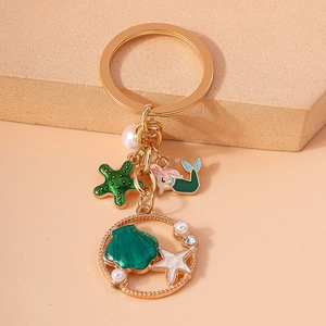 Detail of golden mermaid keychain with green starfish, pearls and shell charms