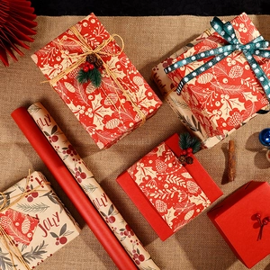 Festive Christmas kraft gift wrapping paper rolls with holly, pine patterns and red ribbons