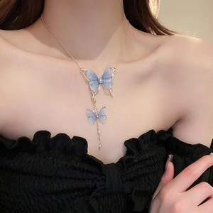 Detail showing elegant gold chain with blue butterfly pendants and pearl tassels on neck