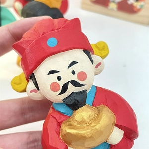 Detail of hand-carved wooden Caishen figurine with visible textures and gold ingot