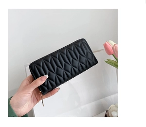 Close-up of black quilted leather lady's purse featuring golden zipper detail