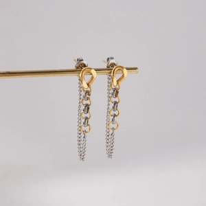 Détail des boucles d'oreilles à pompon bicolores en acier inoxydable doré 18 carats et argent