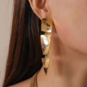 Macro shot of 18k gold plated square twisted drop earrings worn by a model