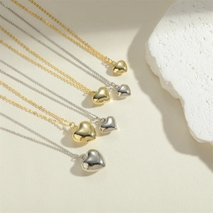 Elegant gold and silver heart pendant necklaces on a natural stone minimalist background