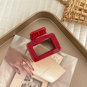 Macro shot of red acetate hair claw clip with gold lettering on a vintage magazine base
