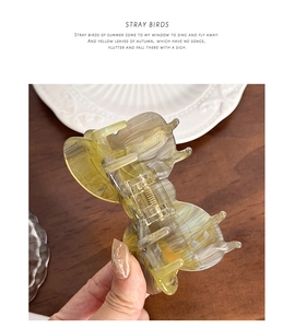 Close-up of translucent marble texture butterfly hair claw clip with gold metal spring
