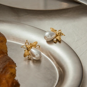 Detail of bee stud earrings with gold plating, teardrop pearl, and sparkling rhinestones