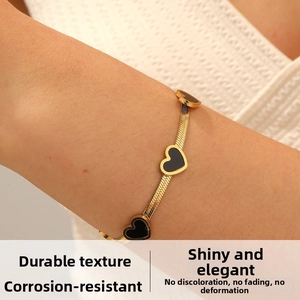 Detail of gold blade chain bracelet with black hearts featuring tarnish-resistant finish