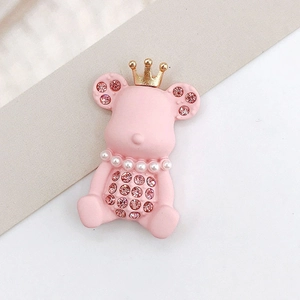 Macro view of pink bear accessory with golden crown and pearl necklace details