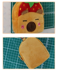 Detail view of yellow capybara plush coin purse with a red strawberry hat and zipper
