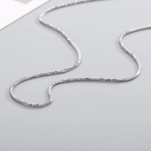 Detailed macro view of a silver titanium steel snake chain showing its twisted texture