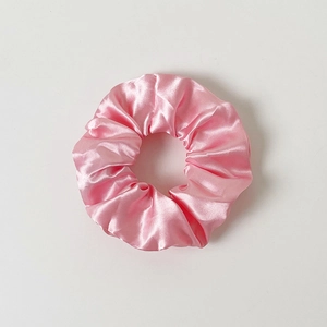 Close-up of pink silk LED scrunchie showing glossy texture and elegant folds