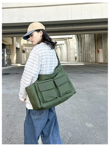 Detail of green canvas crossbody bag with two front flap pockets and sturdy texture