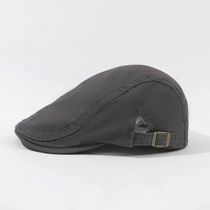 Detail view of dark grey flat cap with bronze metal adjustable buckle and fine stitching