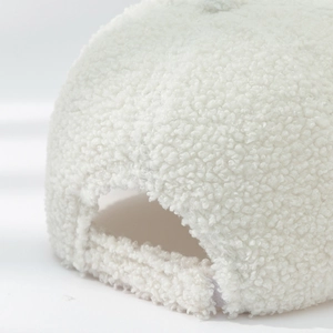 Detailed macro view of the adjustable back buckle on white faux shearling baseball cap