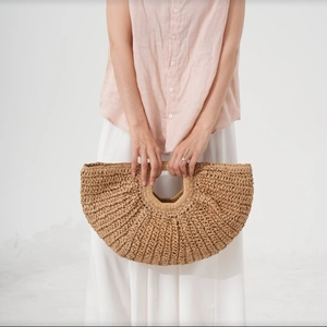 Handwoven brown straw tote bag with round handles, perfect for a vacation beach look