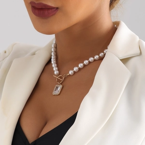 Macro shot of a pearl necklace with golden OT buckle and rectangular crystal pendant