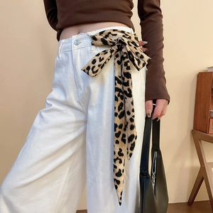 Dettaglio della cintura foulard in seta con stampa leopardata su pantaloni bianchi