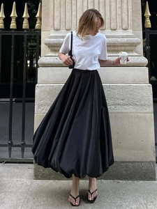 Elegante zwarte geplooide maxi-rok met een wit T-shirt in een chique streetstyle-look