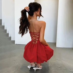 Detail of red backless dress showing cross-strap lacing and structured puff hemline