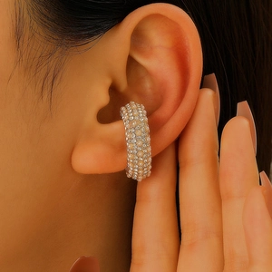 Dettaglio ravvicinato di un ear cuff dorato a C con perle bianche e zirconi scintillanti