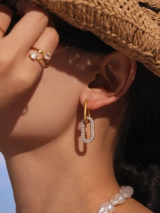 Gros plan de boucles d'oreilles ovales en zircon, bague coeur et collier de perles