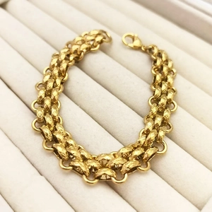 Detail of gold multi-layer chain bracelet with diamond-cut texture in a white jewelry box