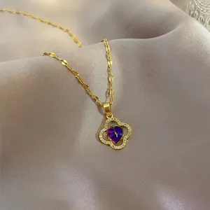 Macro detail of gold four-leaf clover pendant with purple crystal and white zircon inlay