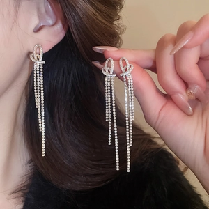 Close-up of sparkling tassel earrings with intricate crystal knots and silver posts