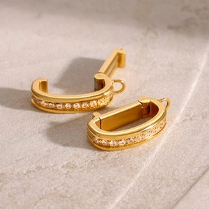 Macro shot of gold D-shape hinged earrings with white cubic zirconia pavé setting