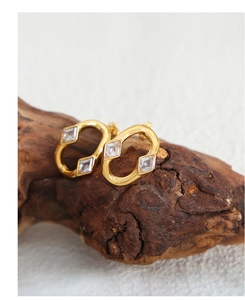 Macro shot of gold oval earrings featuring two square-cut cubic zirconia on wood