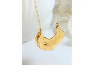 Detail of the golden hammered crescent pendant with unique pleated metal texture