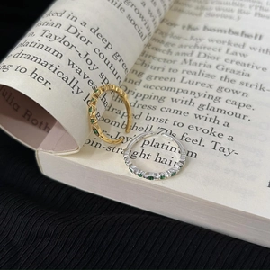 925 silver open rings with green marquise stones in gold and silver finishes on a book
