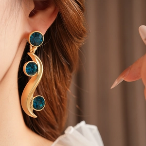 Detail of vintage gold-toned S-curve earrings set with three round blue gemstones