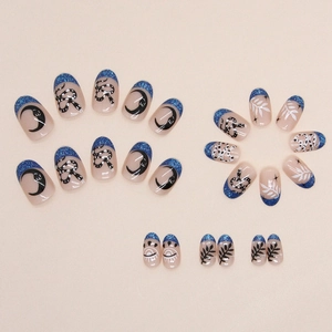 Short oval press-on nails with blue glitter tips, moon and snake patterns on nude base