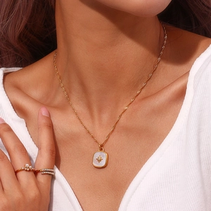Detail of gold square starburst pendant necklace with shell inlay on female model