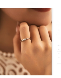 Macro detail of minimalist silver ring featuring a marquise-cut clear gemstone on finger