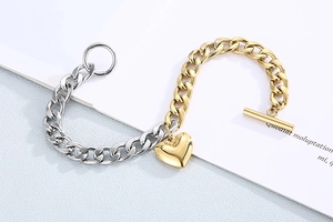 Detail of two-tone gold and silver Cuban chain bracelet with heart pendant and OT toggle clasp